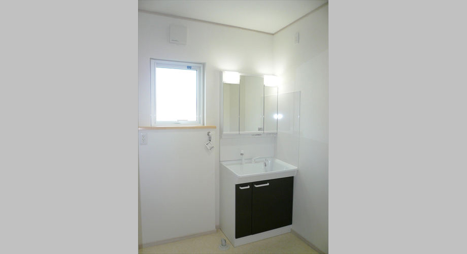 【洗面脱衣室】茶色の木目が印象的な洗面化粧台。鏡の裏面は収納できるようになっております。